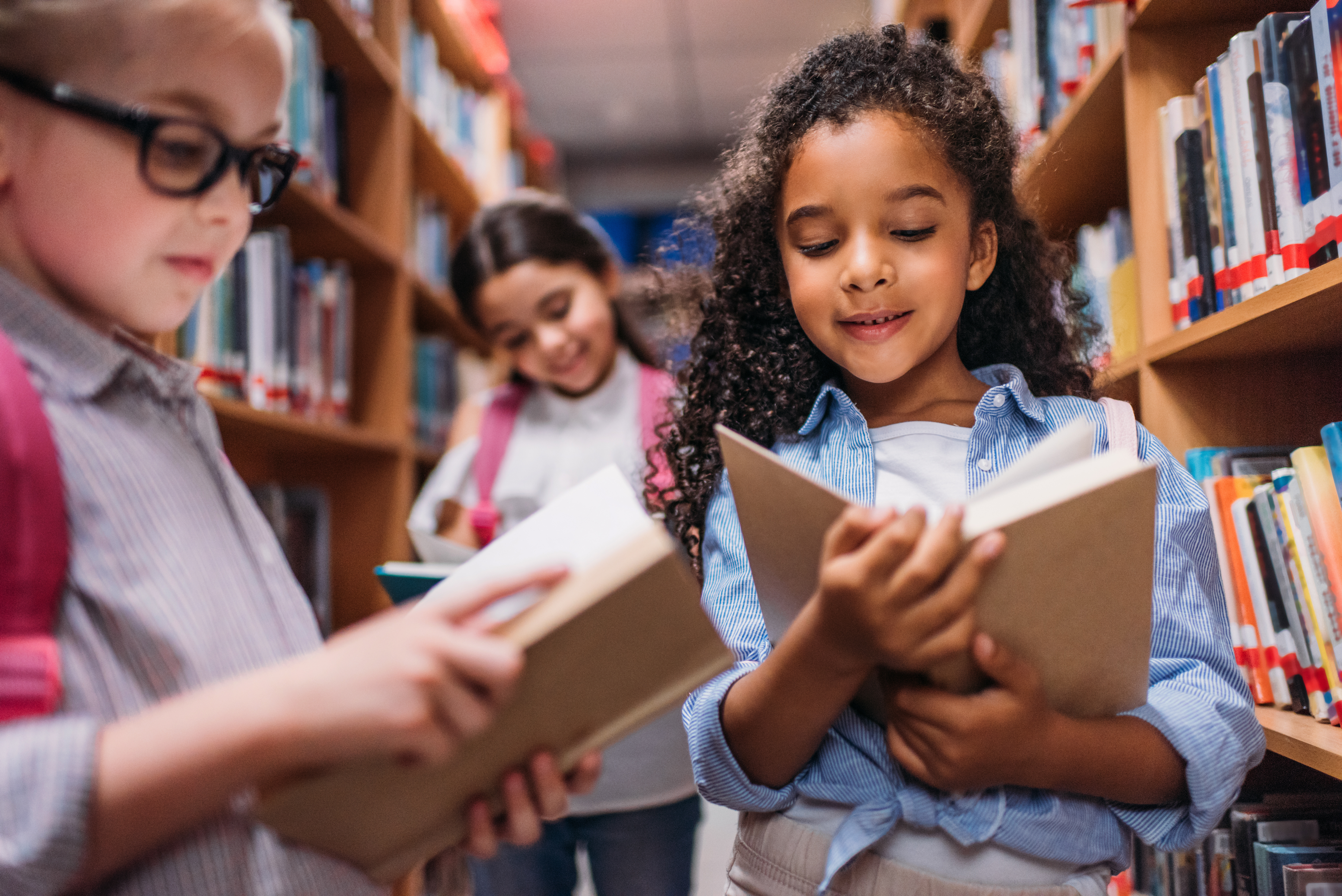 Schoolgirls Looking for Books in Library